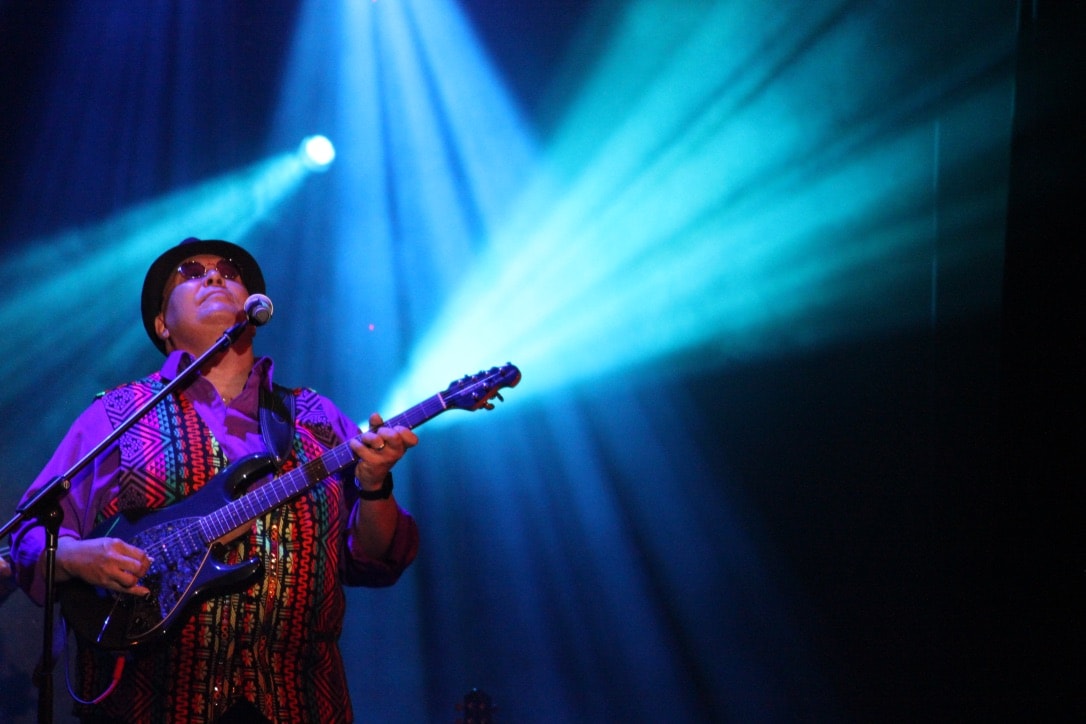 Live guitarist performing under blue stage lights